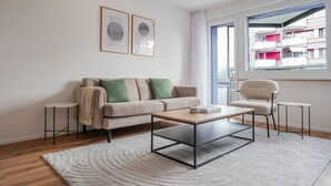 A living room with a sofa, a coffee table, and a chair. There are two framed pictures on the wall. - Blueground | Dietikon, balcony, nr Bahnhof (Zurich)