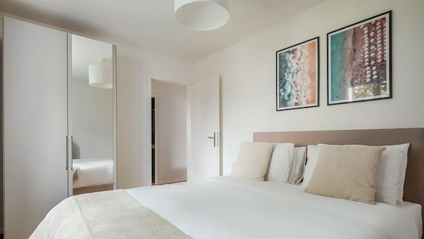 A bedroom with a large bed, a wardrobe, and two framed pictures on the wall. - Blueground | Dietikon, balcony, nr Bahnhof (Zurich)