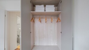 A walk-in closet with wooden shelves, a hanging rod, and a door leading to a bathroom. - Blueground | Dietikon, balcony, nr Bahnhof (Zurich)