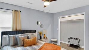 A bedroom with a bed, bedside table, lamp, mirror, and a closet.