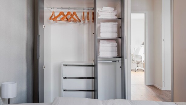 Quarto moderno com closet espaçoso, cama e área de trabalho.