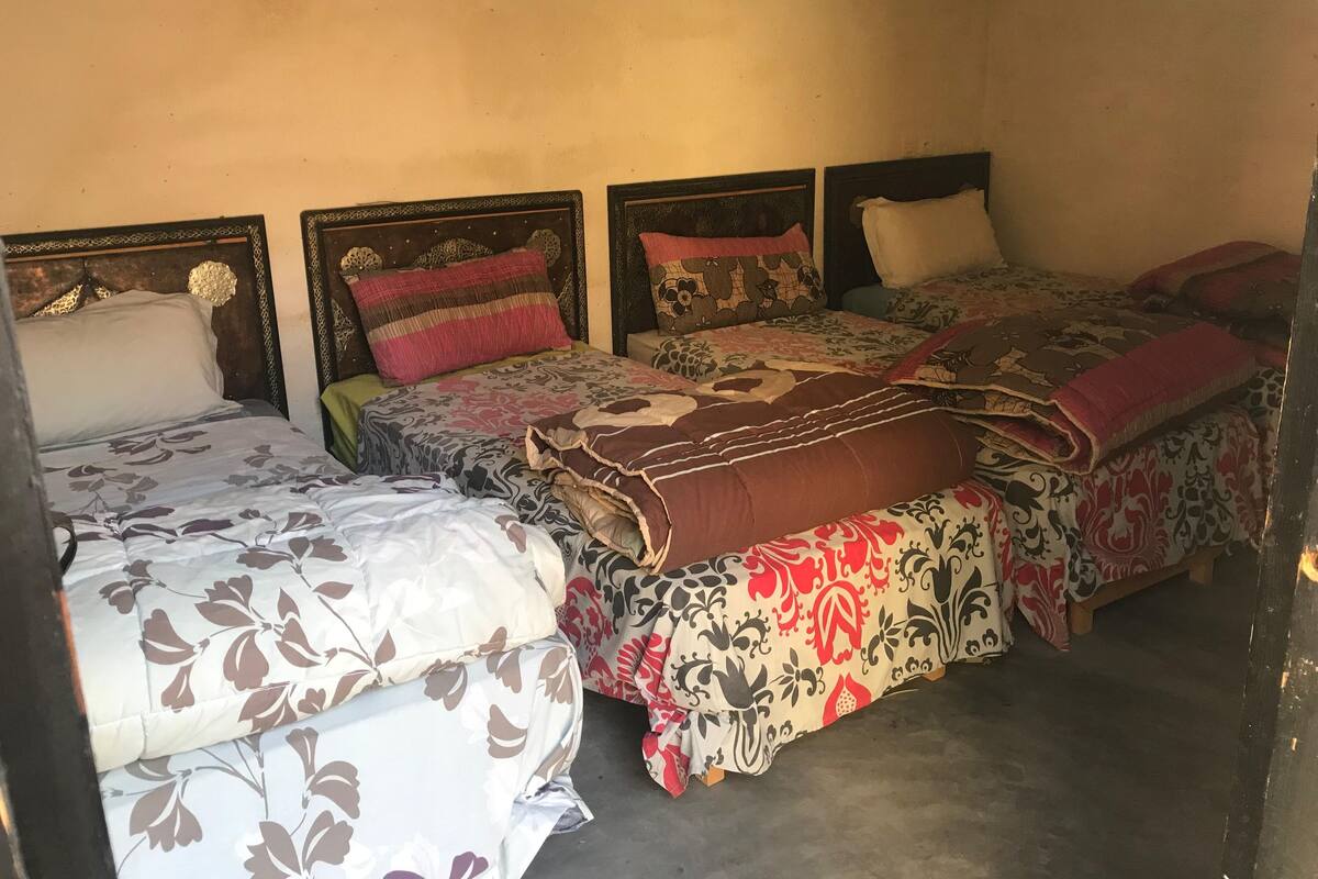 A room with three beds, each with different patterned bedspreads.