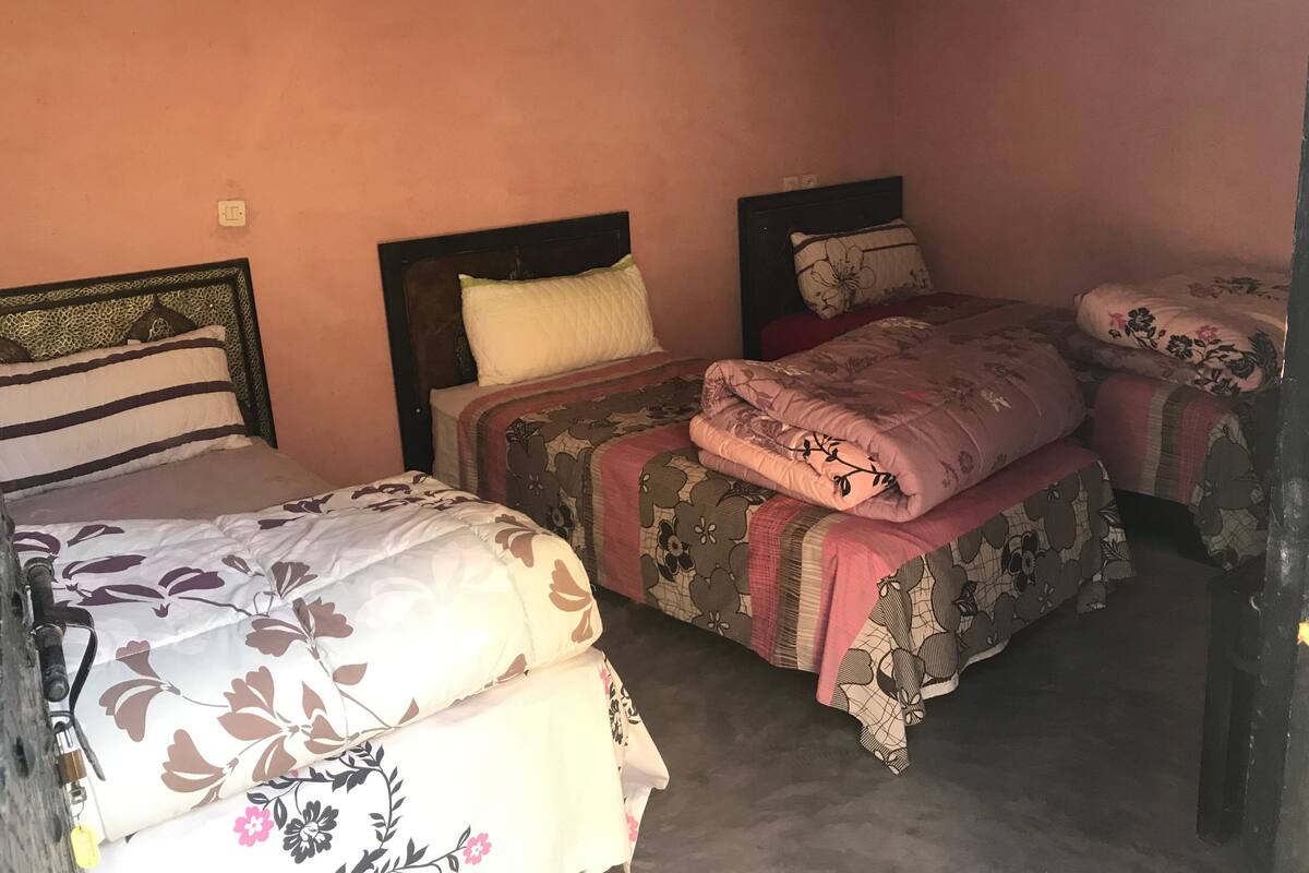 A bedroom with two beds, each with floral-patterned bedding and a wooden headboard.