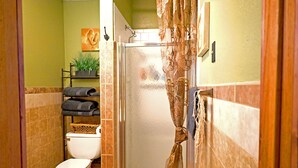 Een badkamer met een douchecabine van glas, toilet, wastafel en een handdoekrek met opgevouwen handdoeken.