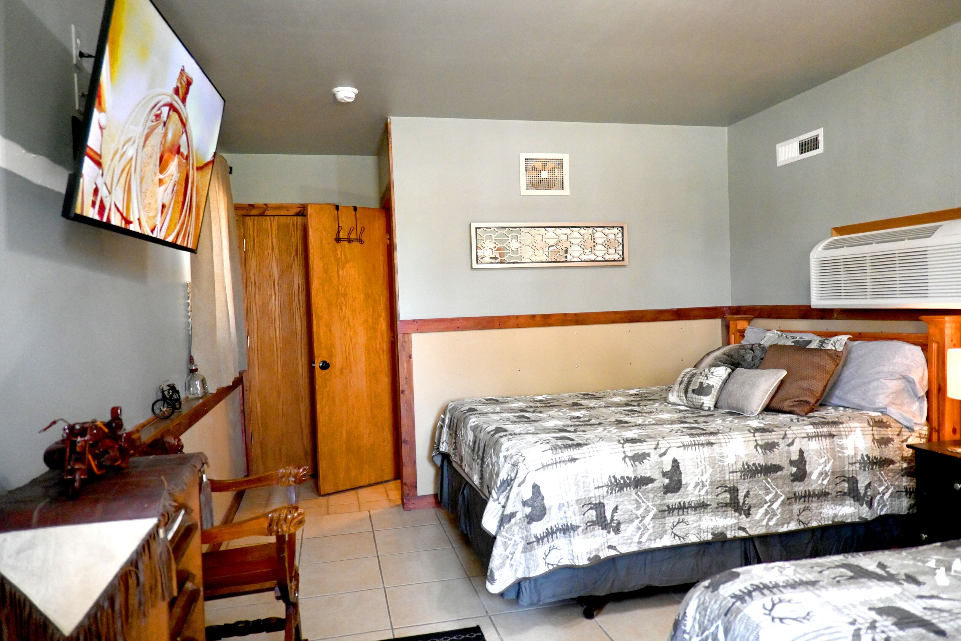A bedroom with a bed, a desk, a chair, a television, and a wardrobe.