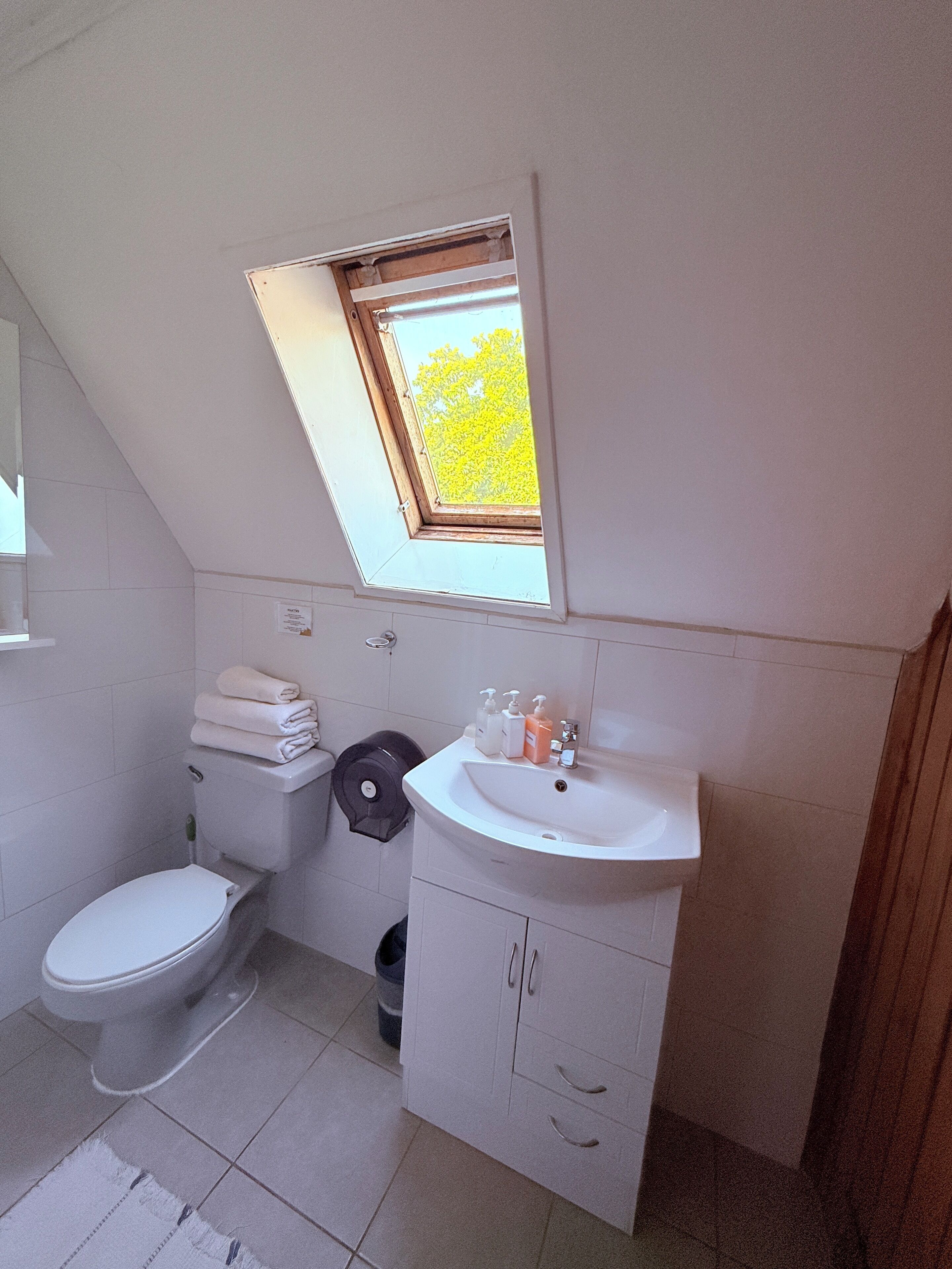 A small, clean bathroom with a toilet, sink, and a window above the sink.