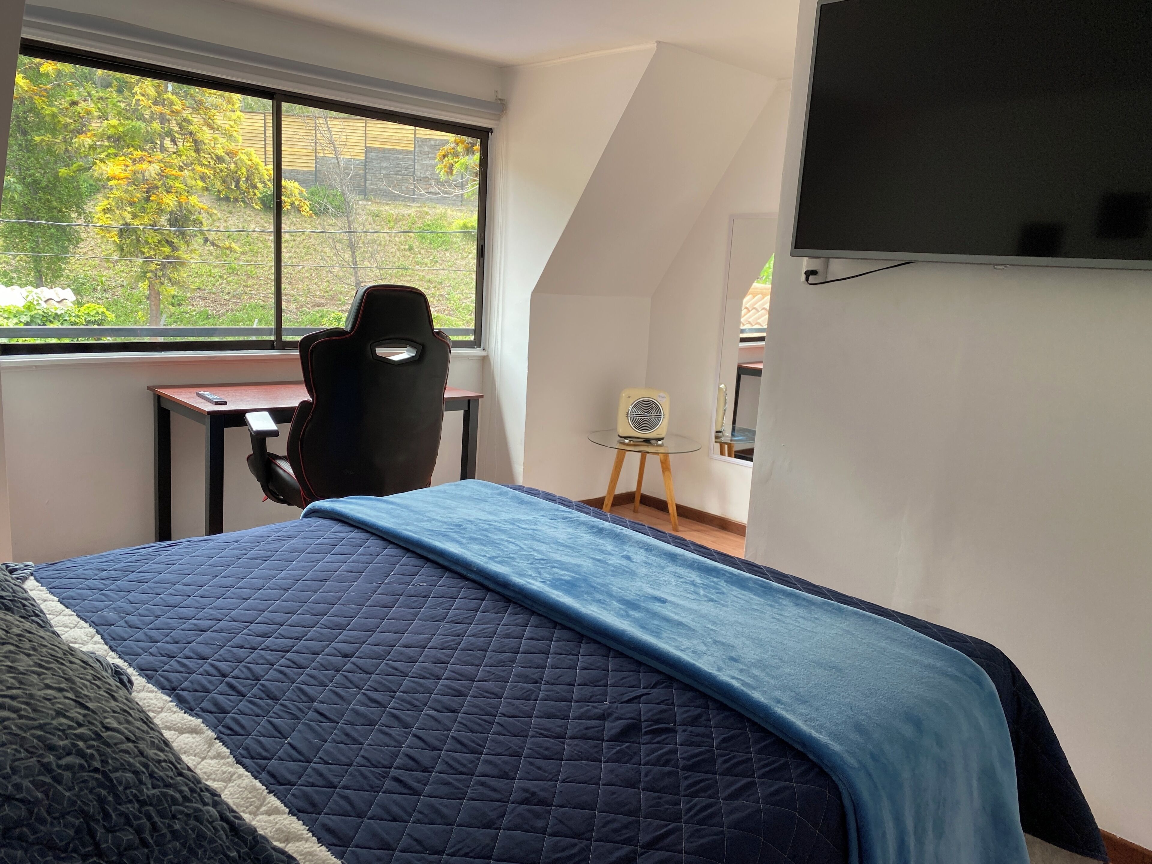A bedroom with a bed, a desk, and a chair.