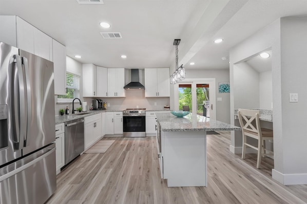A modern kitchen with stainless steel appliances, white cabinetry, and a central island.