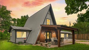 Une maison moderne avec un toit en pente, un patio couvert et un petit jardin.