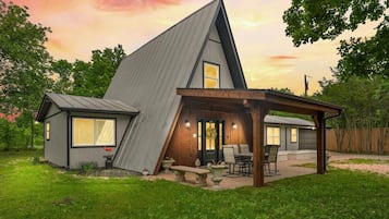 Une maison moderne avec un toit en pente, un patio couvert et un petit jardin.