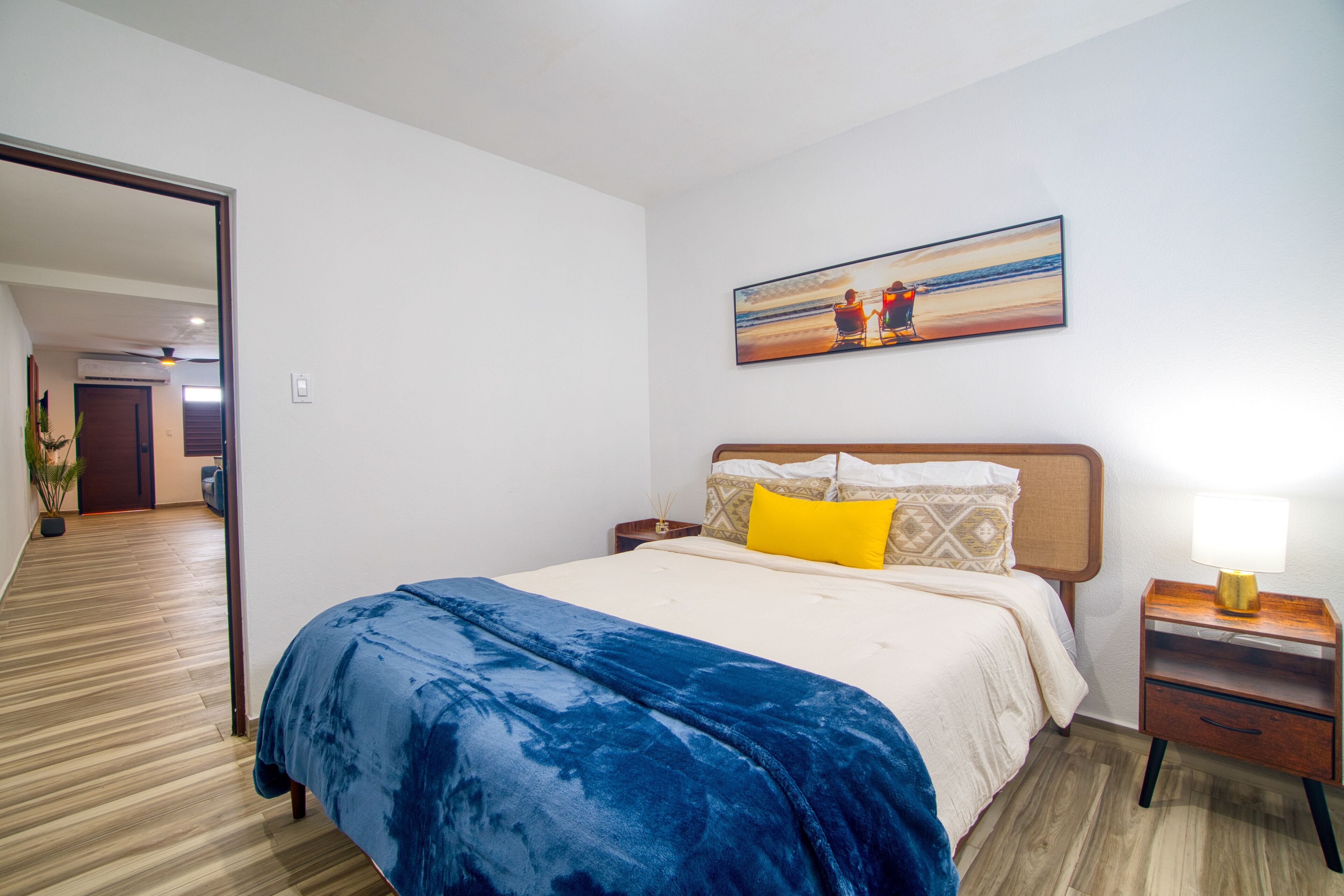 Una habitación de hotel con una cama grande, una mesita de noche, una lámpara y un cuadro en la pared.