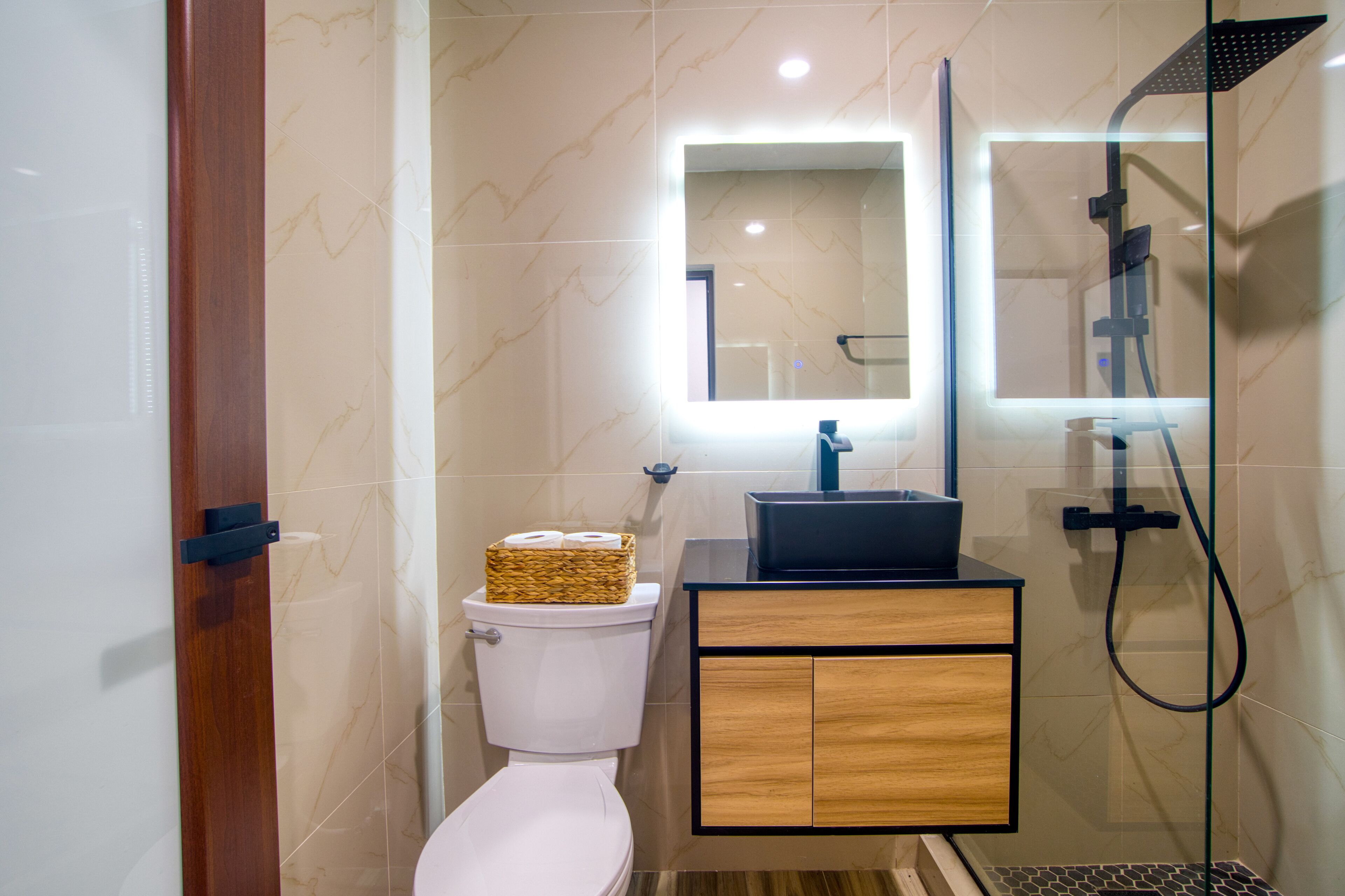 Een moderne badkamer met toilet, wastafel met spiegel en douche.