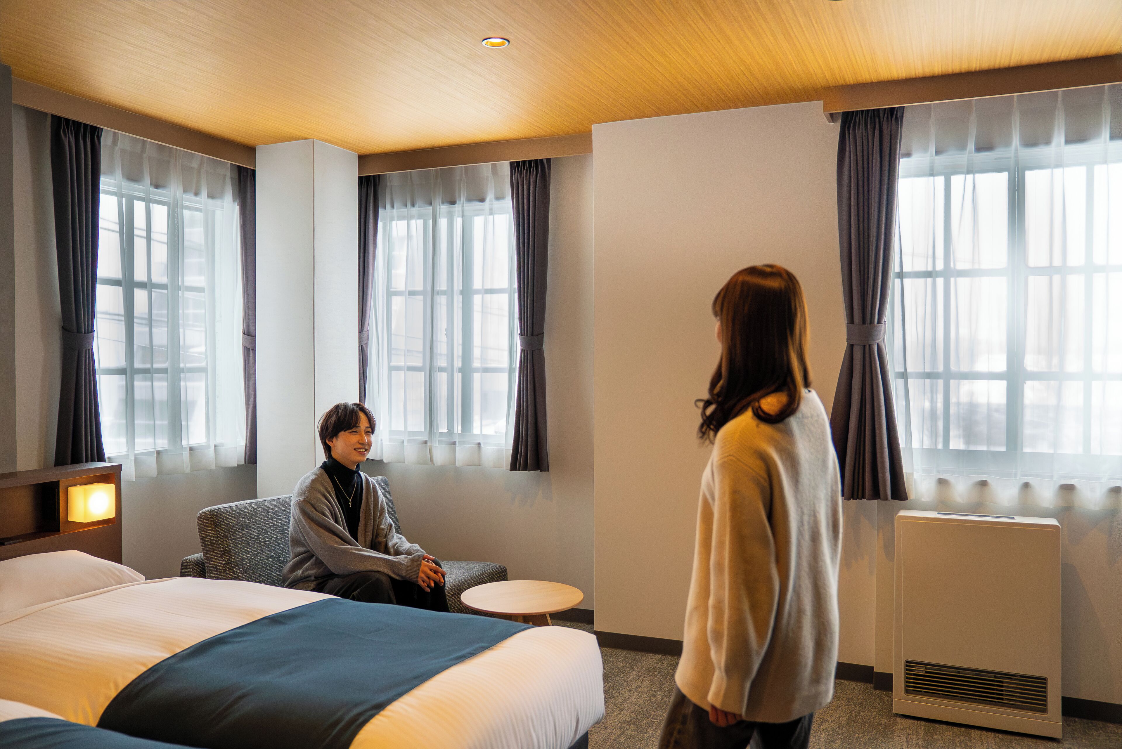 Una habitación de hotel con una cama, una silla, una mesita y un calentador.