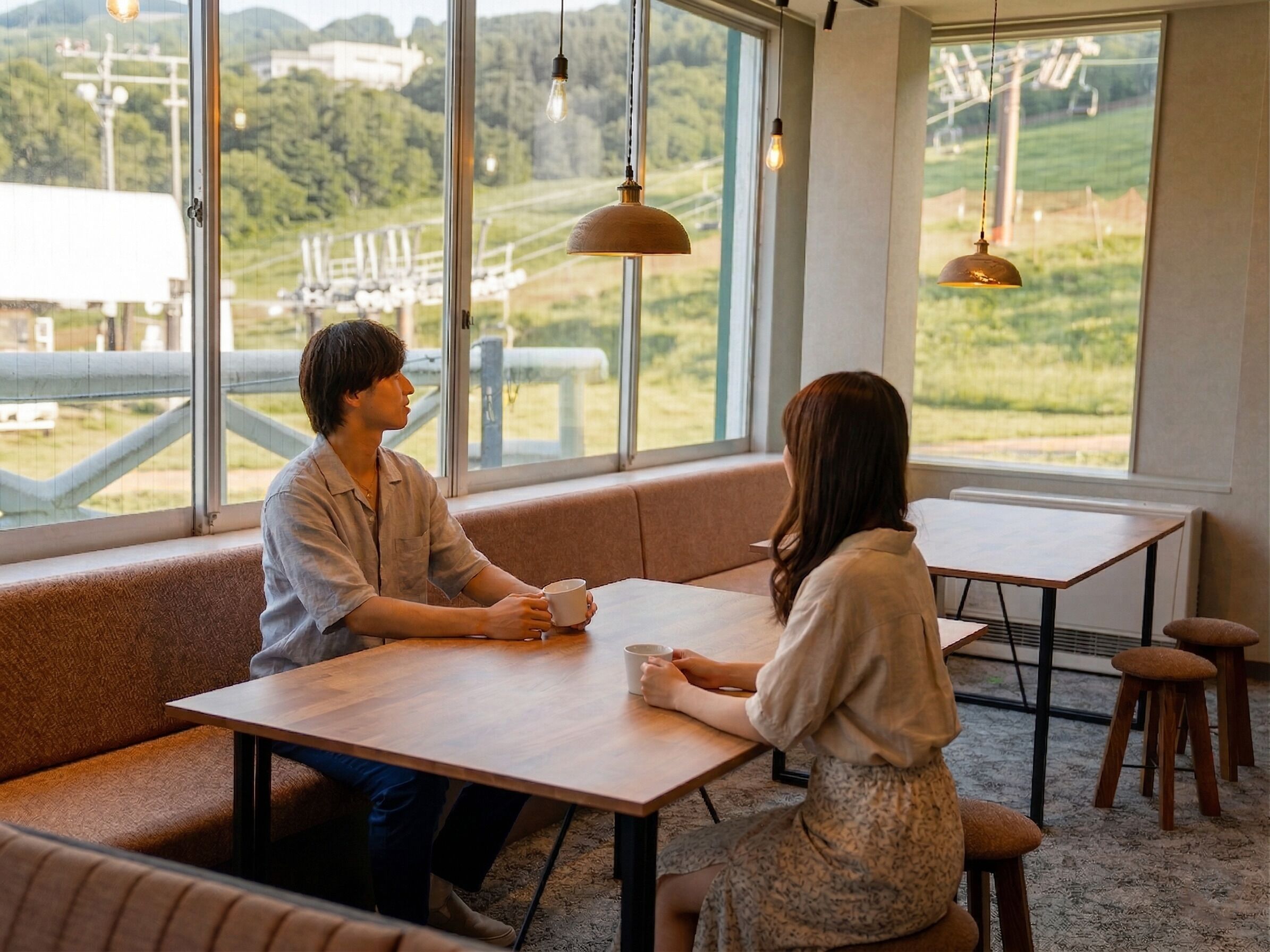 A cozy café with large windows, a wooden table, and a bench.