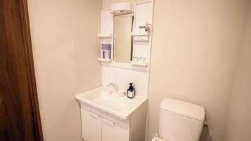A bathroom with a white sink, mirror, and toilet.