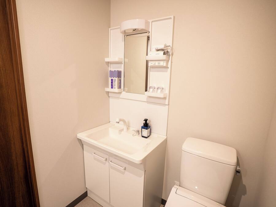 A bathroom with a white sink, mirror, and toilet.