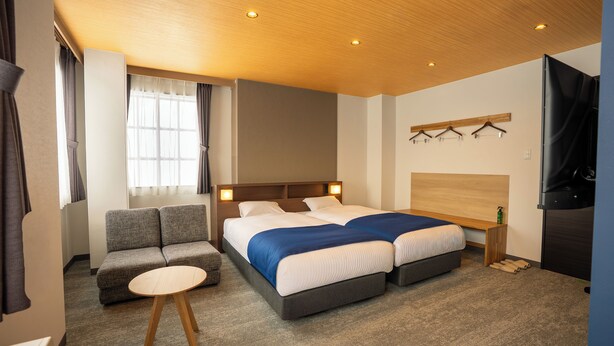 A modern hotel room with a large bed, a sofa, a small table, and a TV. - YuiLocalZao (Yamagata)