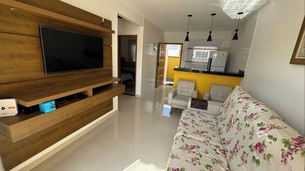 Un salon moderne avec un téléviseur à écran plat, un meuble de rangement en bois et un canapé à motifs floraux.