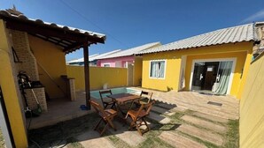 Un jardin avec une piscine, une table de patio avec des chaises et un espace abrité.