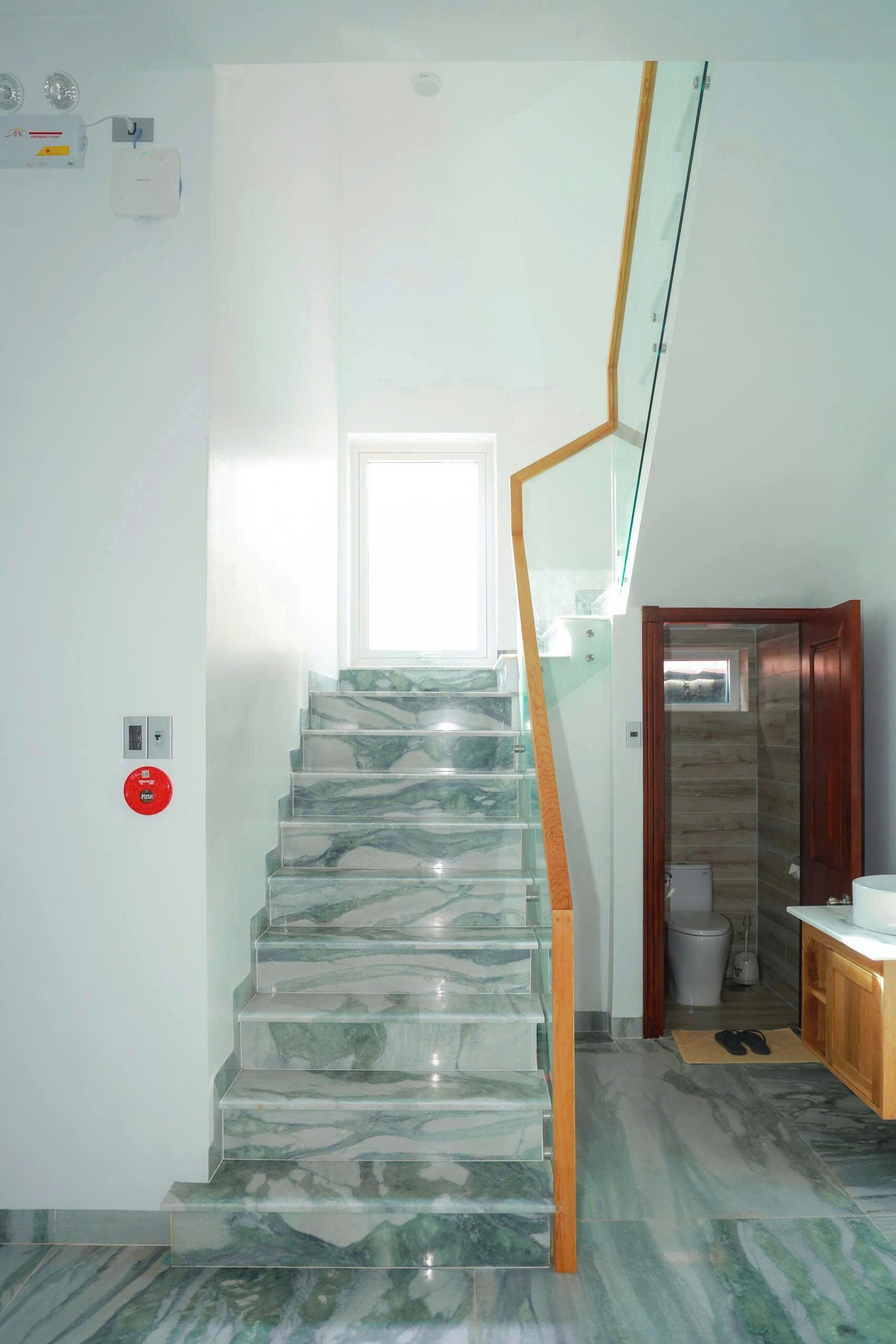 A staircase with marble steps, a wooden handrail, and a glass railing.