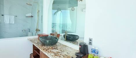 A modern bathroom with a glass shower enclosure, a marble countertop, and a black dishwasher.