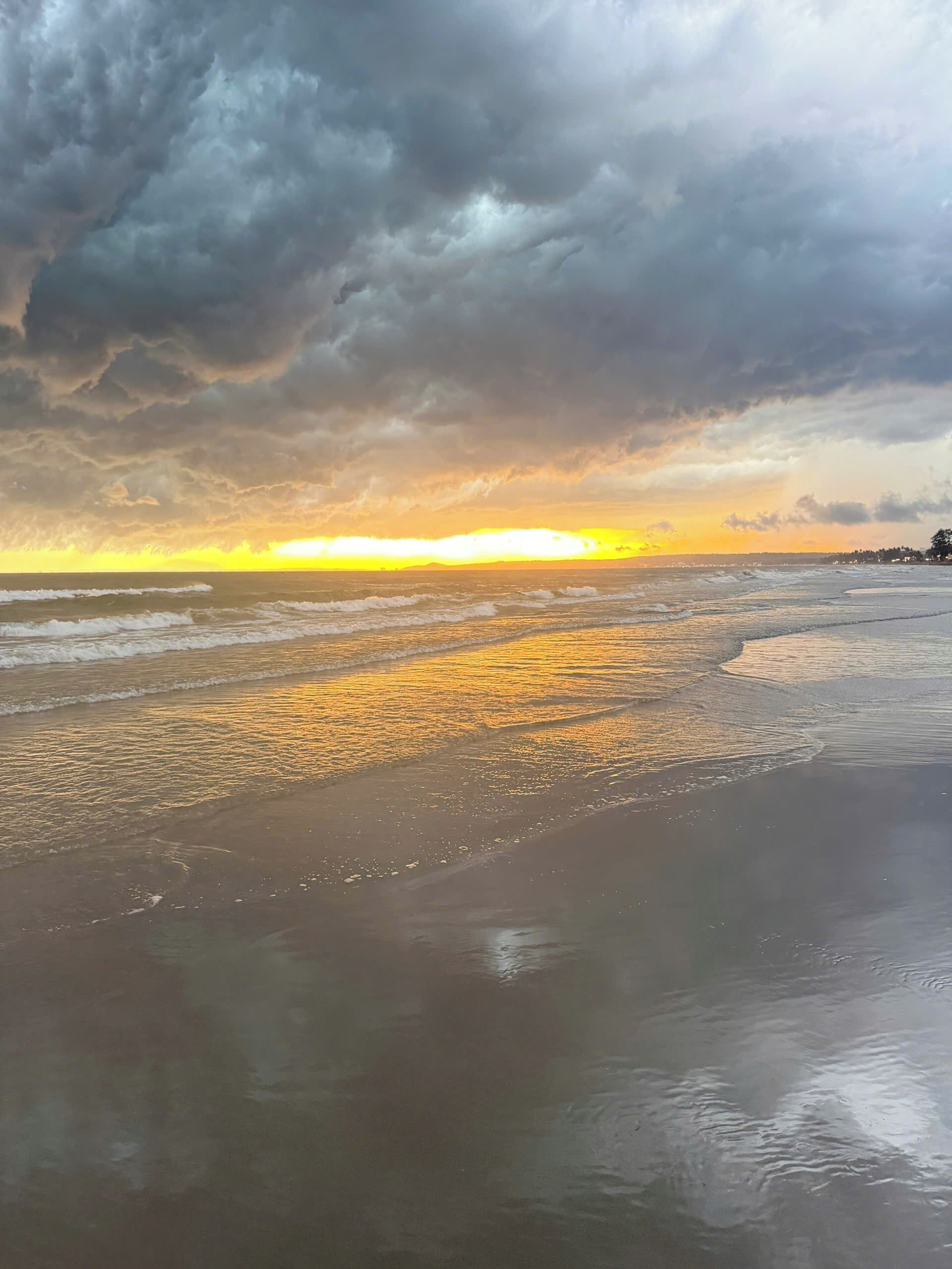 Une plage avec des vagues et un ciel nuageux.