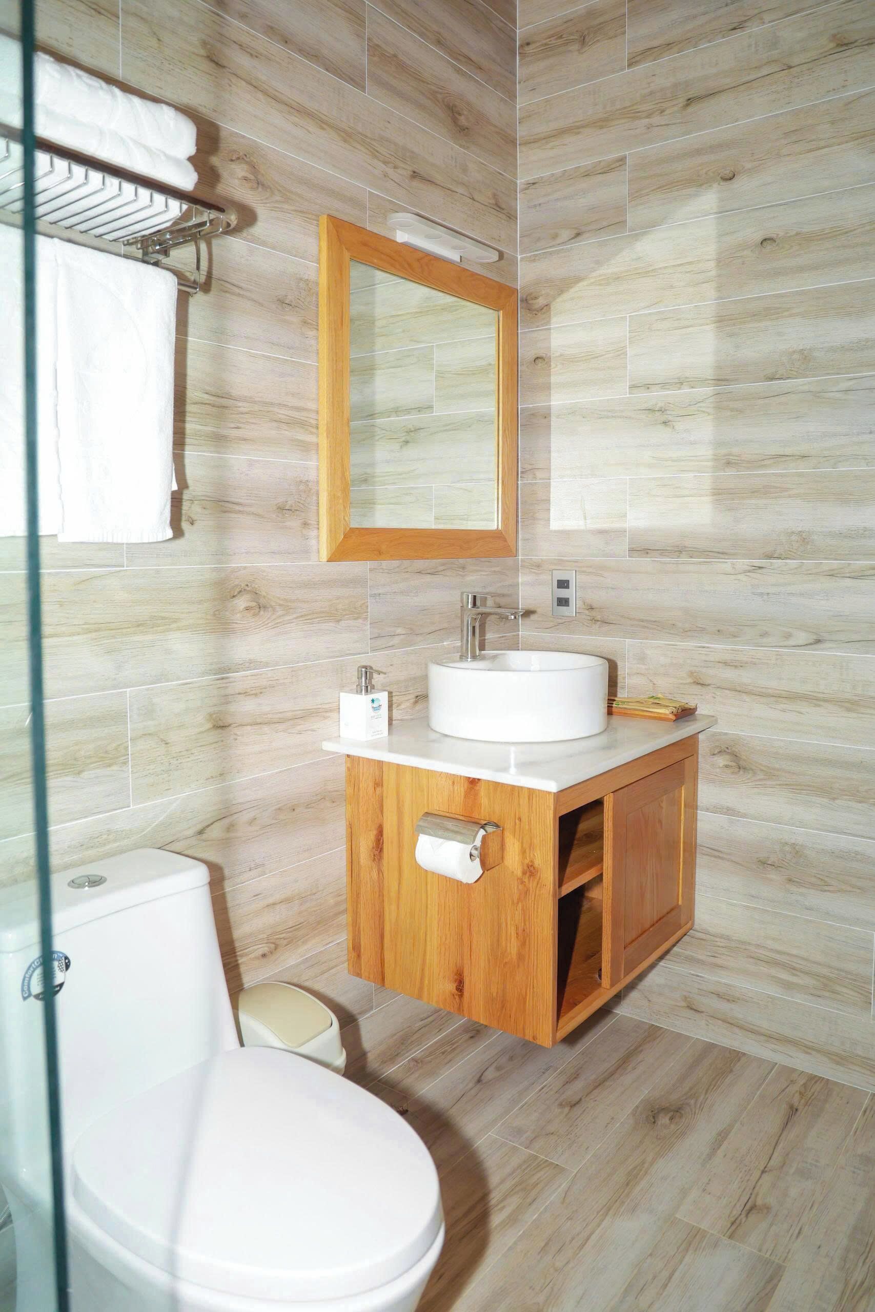 Une salle de bain moderne avec un meuble-lavabo en bois, un lavabo blanc et une cabine de douche en verre.