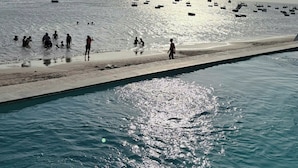 Una playa con barcos, gente y un cielo despejado.