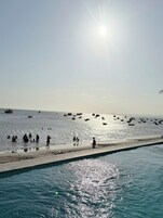 A beach with boats, people, and a clear sky.