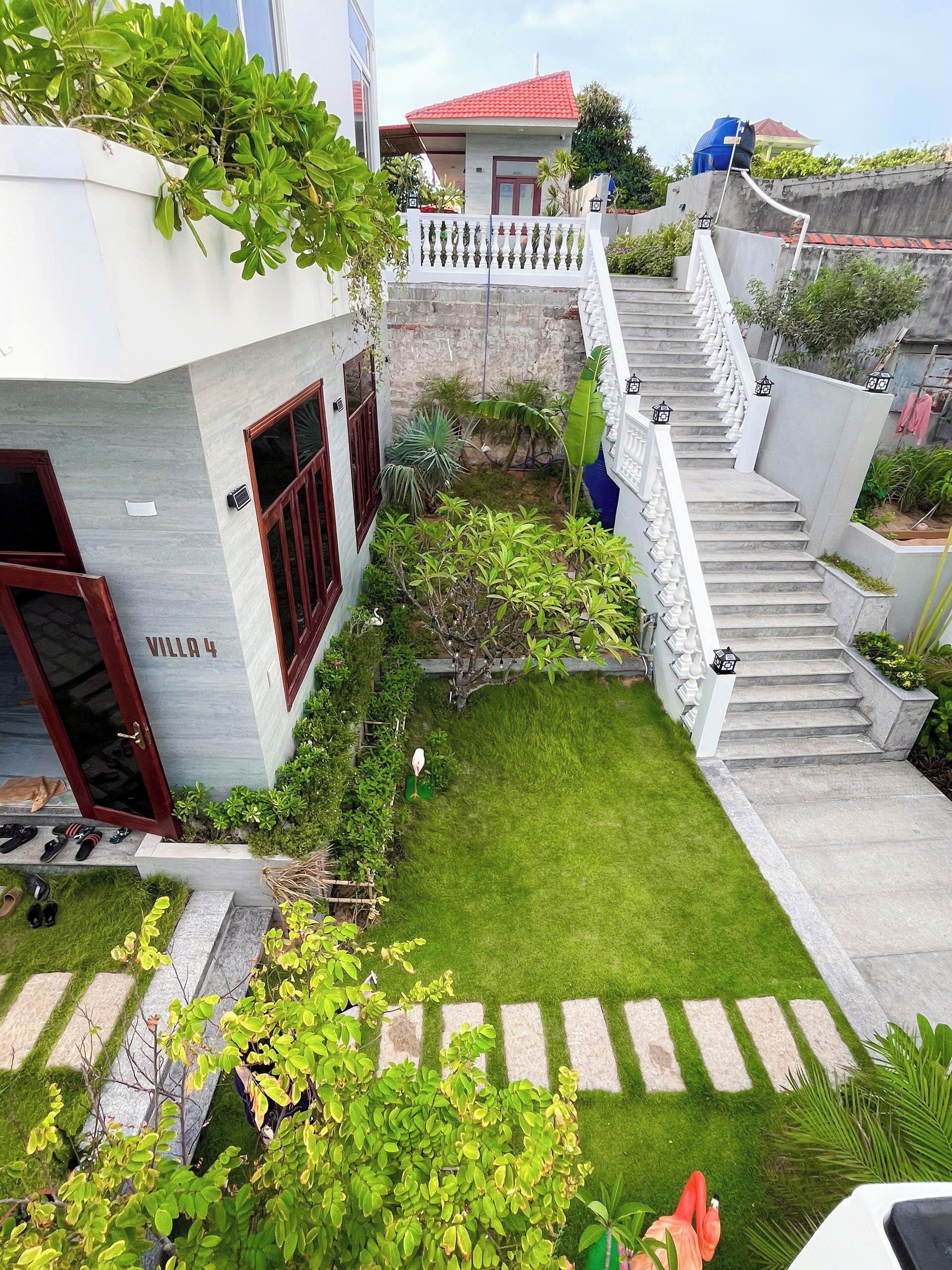 A residential property with a well-maintained lawn, a staircase leading to a second floor, and a small garden area with various plants.