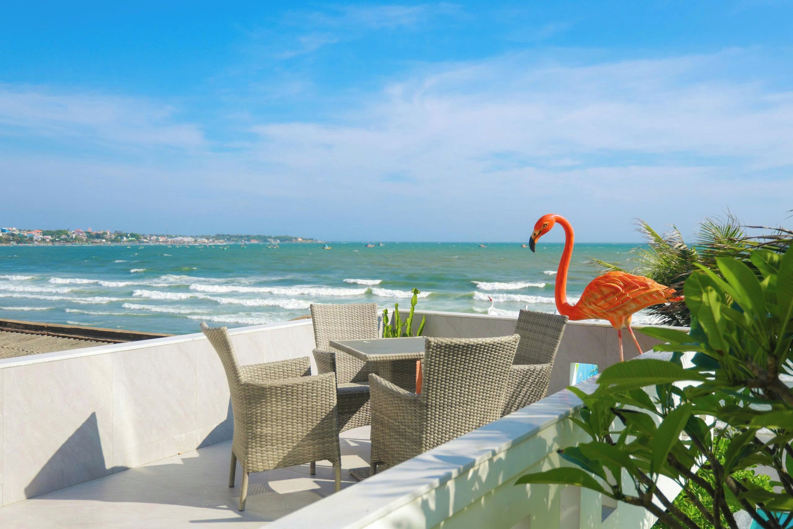 Una terrazza con mobili in vimini, una scultura di fenicottero e vista sull'oceano.