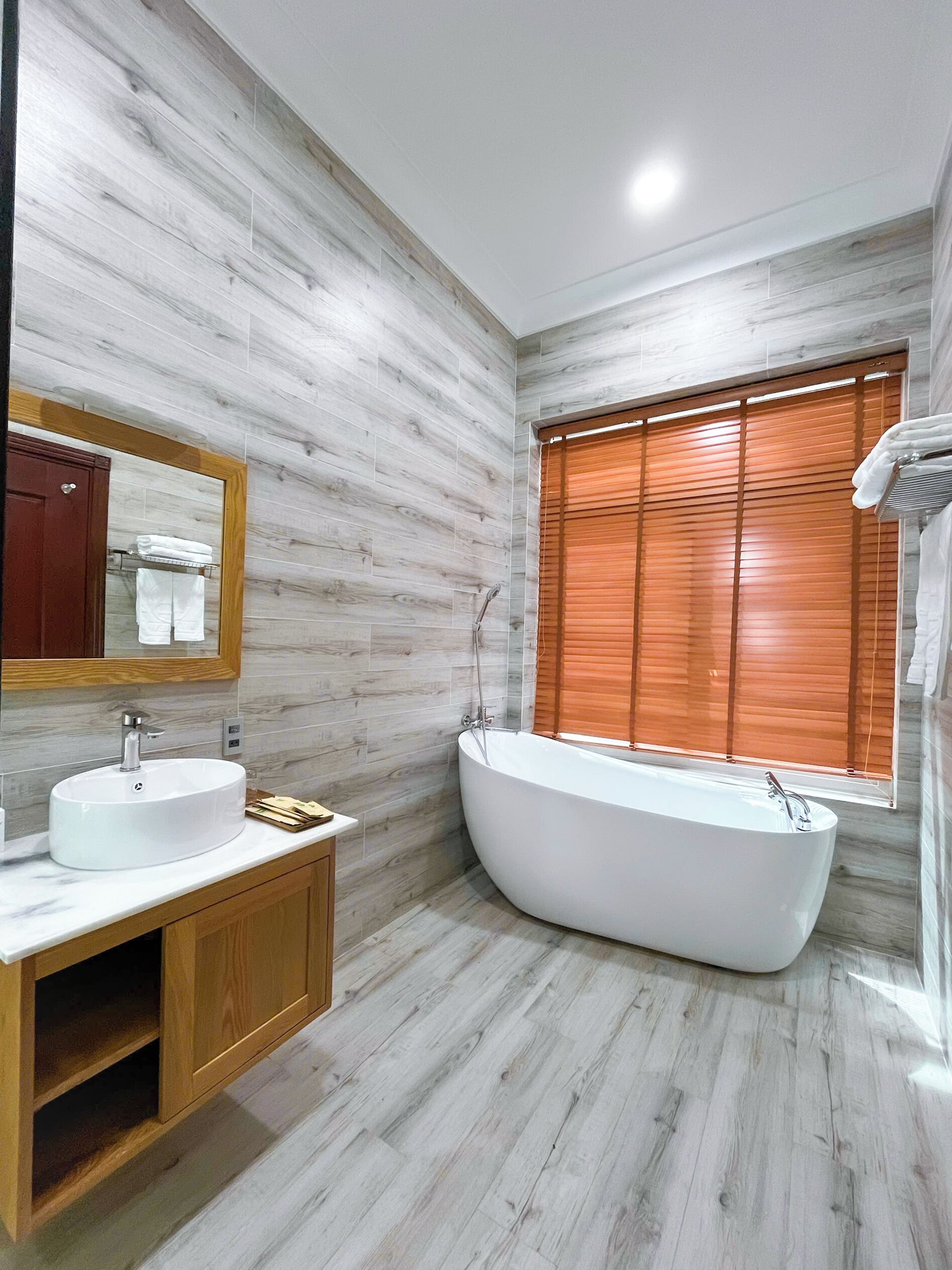 A modern bathroom with a freestanding bathtub, a vanity with a sink, and a large mirror.