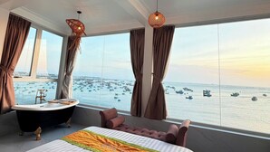 Un dormitorio con una cama grande, una bañera y vistas a barcos en el agua.