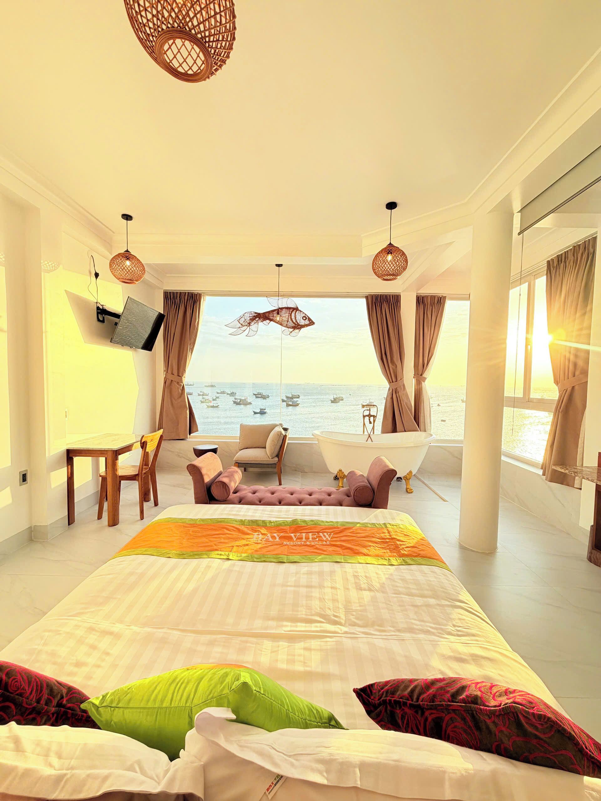 A bedroom with a bed, a sofa, a table, and a view of the sea.