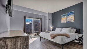 Un dormitorio moderno con cama, mesita de noche y vistas al exterior por un ventanal corredera.