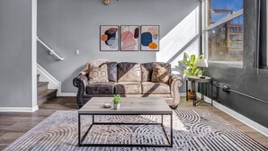 Un moderno salón con un sofá de cuero, una mesa de centro y arte abstracto en la pared.