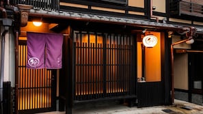 Een traditioneel Japans gebouw met een houten poort, een paarse vlag en een neonbord.