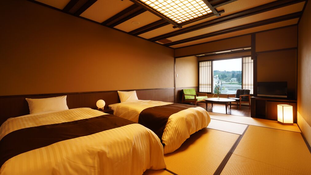 A hotel room with two beds, a small table, a chair, a television, and a view of the outside.