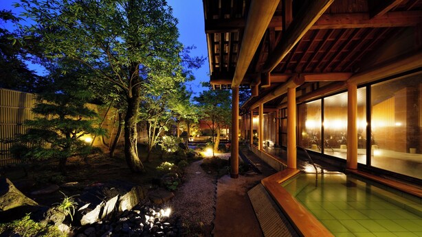 A traditional Japanese-style building with a wooden exterior, a koi pond, and a stone pathway. - Tsukioka Onsen Masyuu (Shibata)