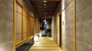 A corridor with wooden sliding doors, a tiled floor, and a ceiling with recessed lighting. - Tsukioka Onsen Masyuu (Shibata)