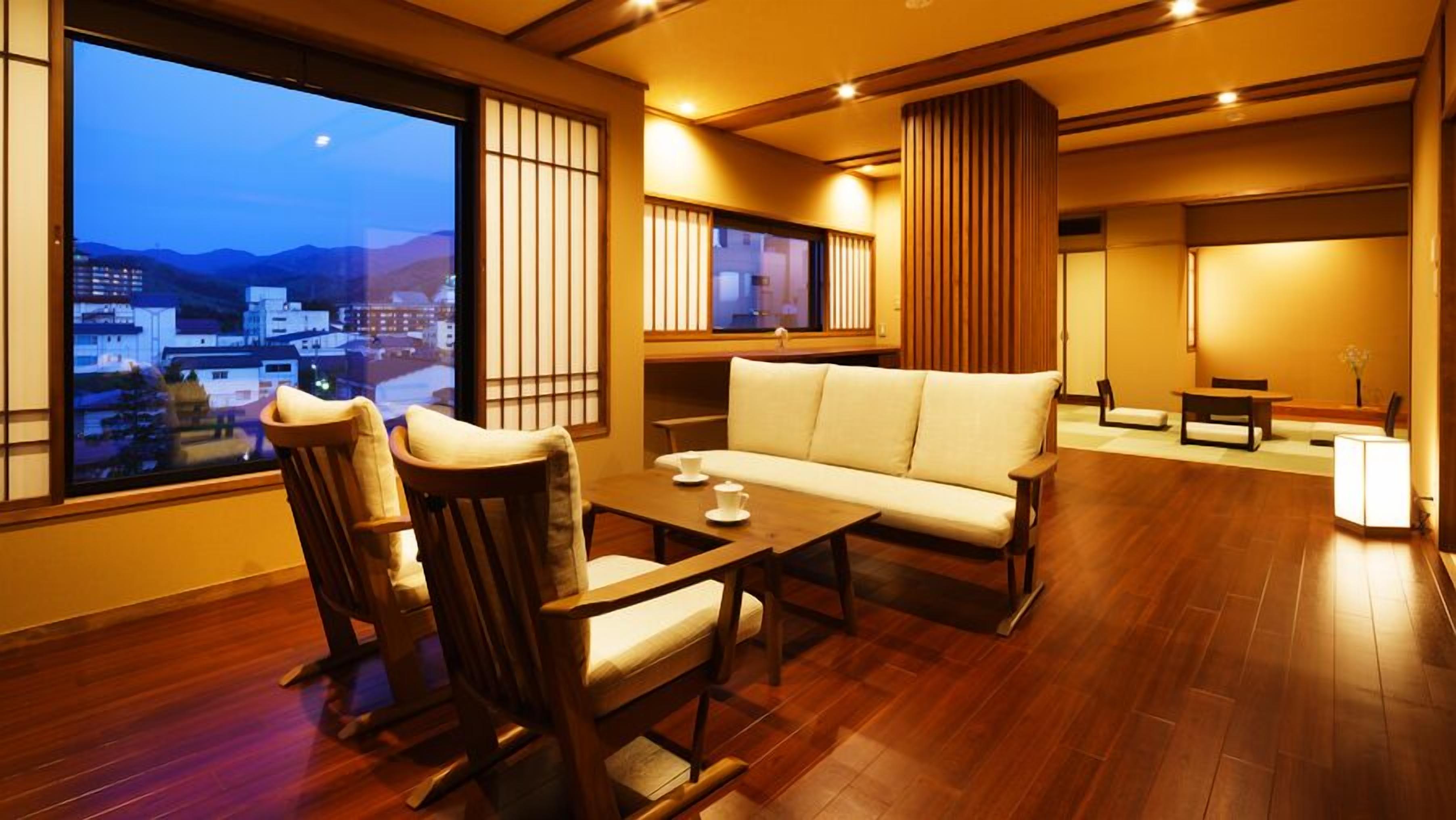 A traditional-style room with a sofa, chairs, a table, and a view of a cityscape.