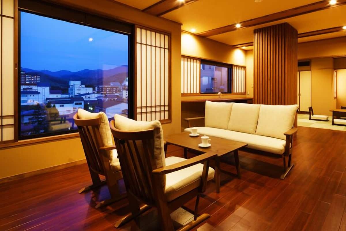 A traditional-style room with a sofa, chairs, a table, and a view of a cityscape.