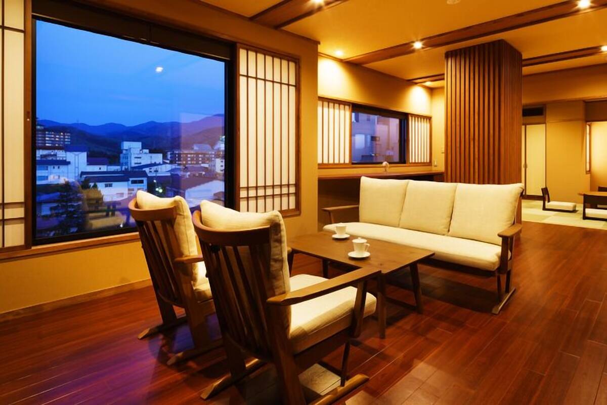 A traditional-style room with a sofa, chairs, a table, and a view of a cityscape.
