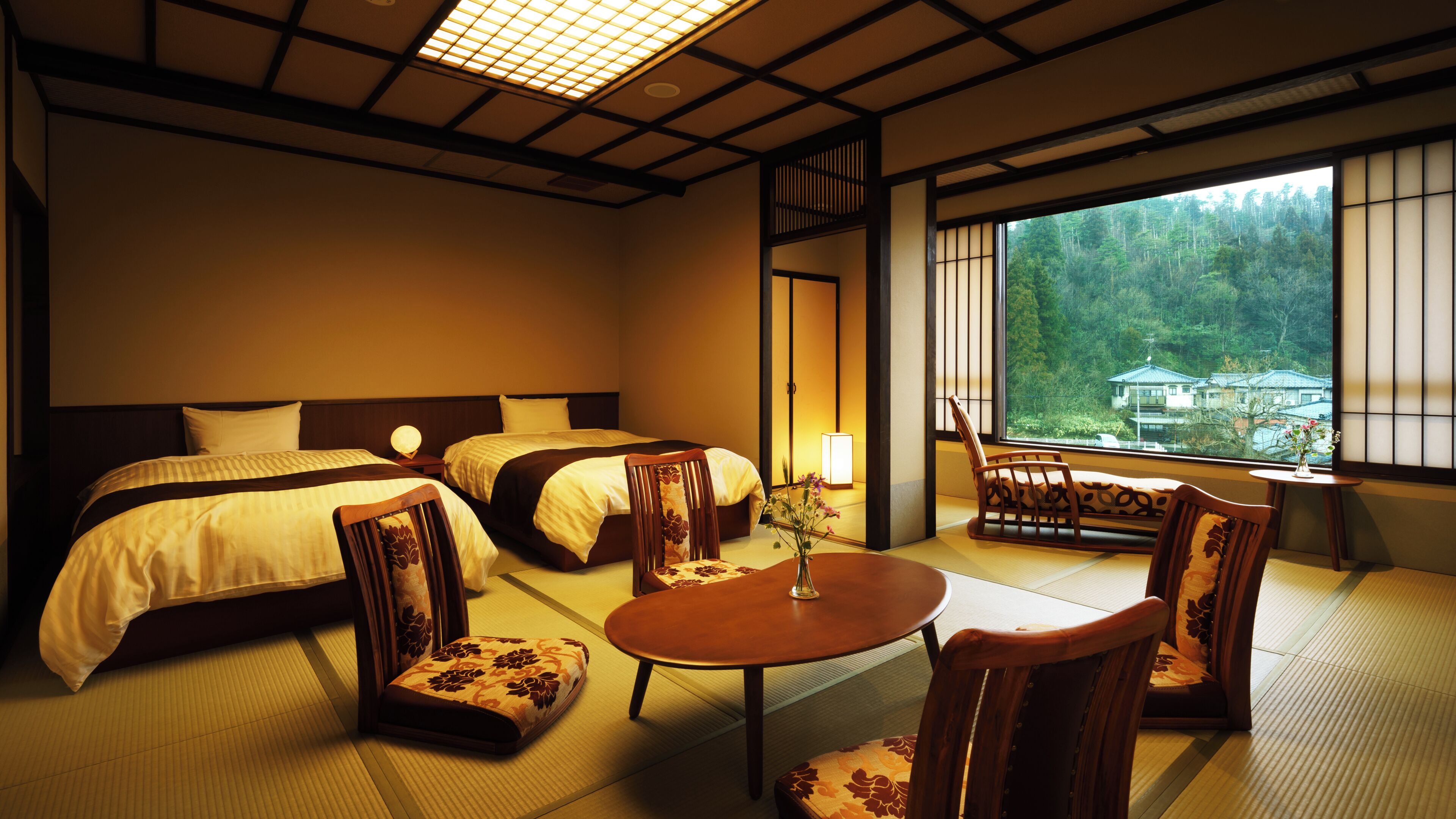 Quarto de hotel tradicional em estilo japonês, com tatames, duas camas, uma pequena mesa e cadeiras.