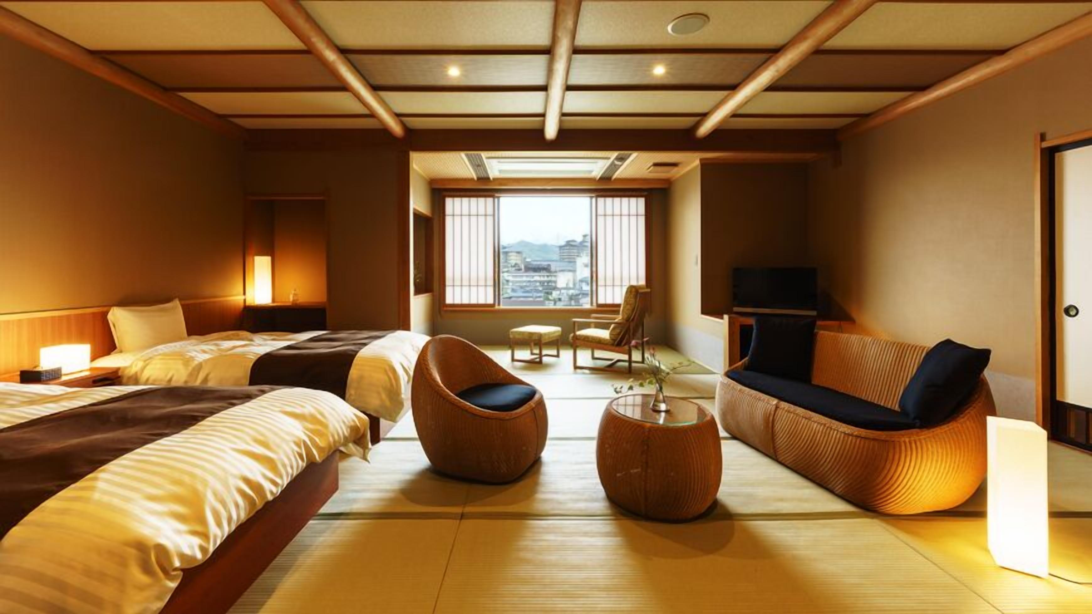 A hotel room with two beds, a sofa, a chair, a small table, and a TV.