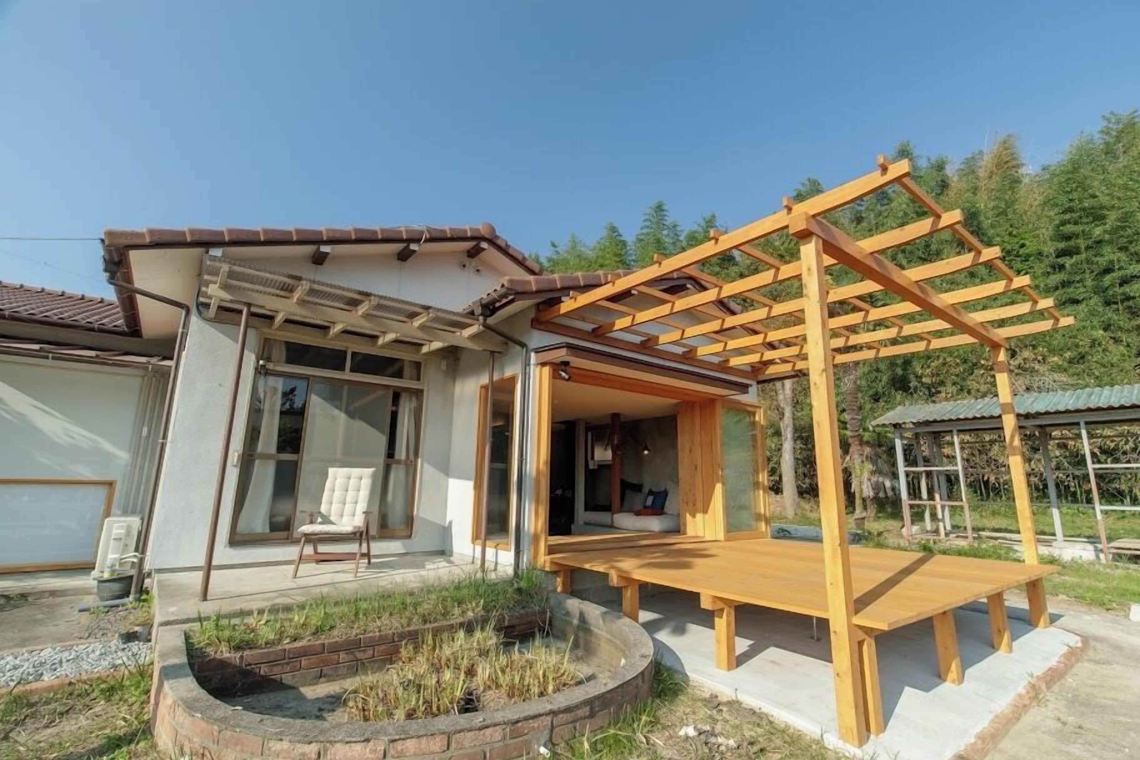A modern house with a wooden pergola, a patio, and a garden area.