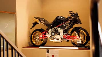 Une moto exposée sur un présentoir fixé au mur, dans une pièce dotée d’un escalier.