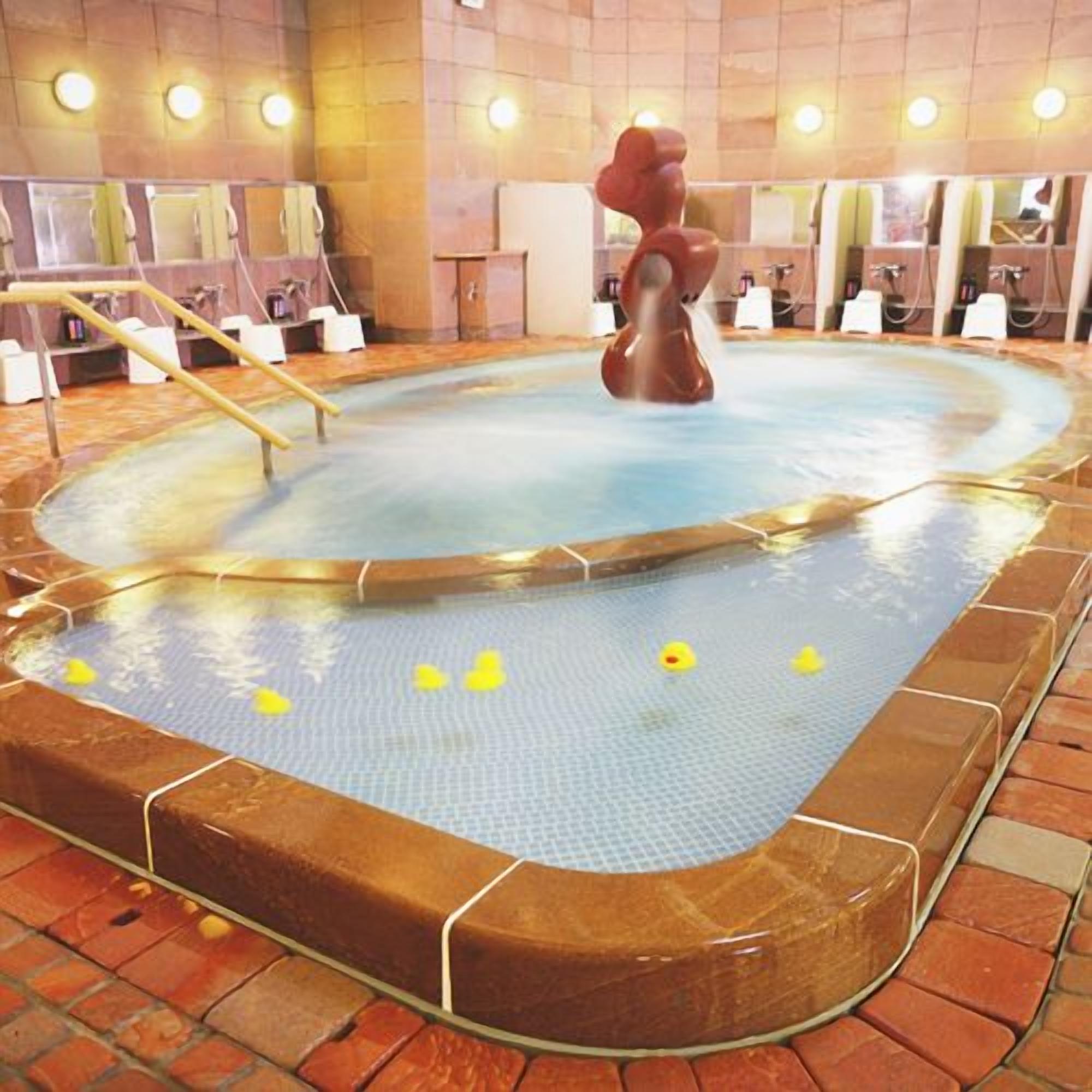 Un bain à remous agrémenté d’une sculpture originale au centre, entouré d’un sol carrelé et bordé de briques.