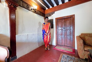 A person standing in a room with a wooden door and a patterned rug. - Fort Jadhavgadh (Sasvad)