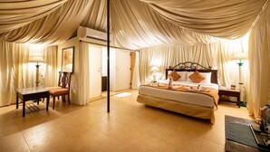 A spacious bedroom with a large bed, a desk, and a chair. - Fort Jadhavgadh (Sasvad)